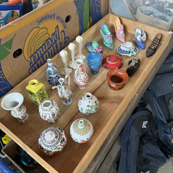 Collection of various ceramic items and decorative shoe & hat figures in a wooden box.