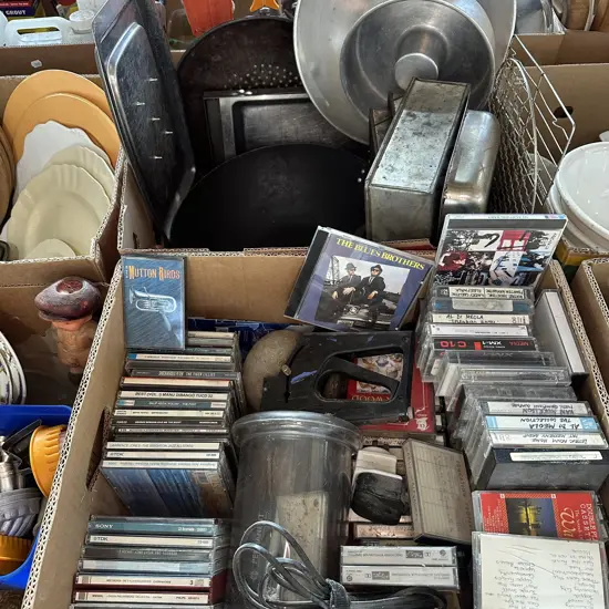 Two boxes large wok, meat carving tray, baking tins, CDs and tapes etc.