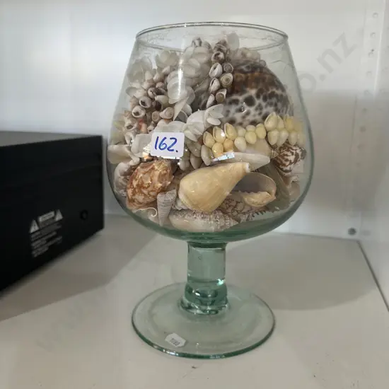 Large pedestal vase with mixed seashells.