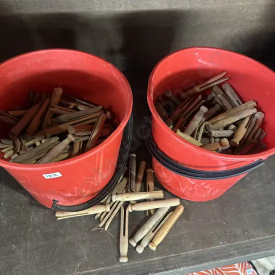 Two buckets of wooden clothers pegs.