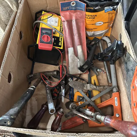 Bin of tools including multimeter and battery charger.